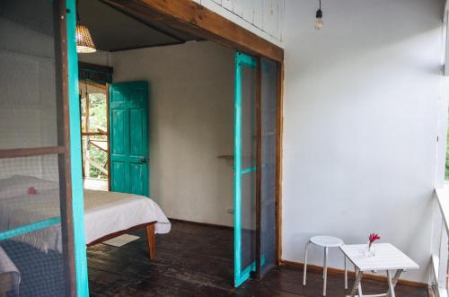a room with a bed and a door with a table at Casa BOHÖ in Puerto Viejo