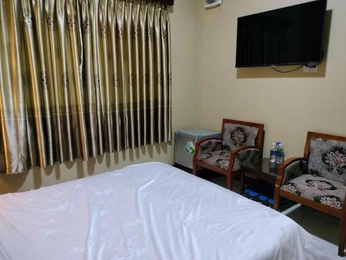 um quarto com uma cama e 2 cadeiras e uma televisão de ecrã plano em Tam Tin Hotel em Ho Chi Minh