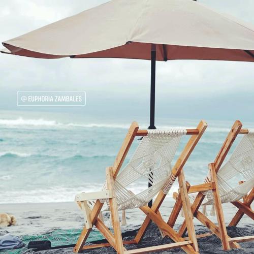 two chairs and an umbrella on the beach at Euphoria Zambales in Botolan