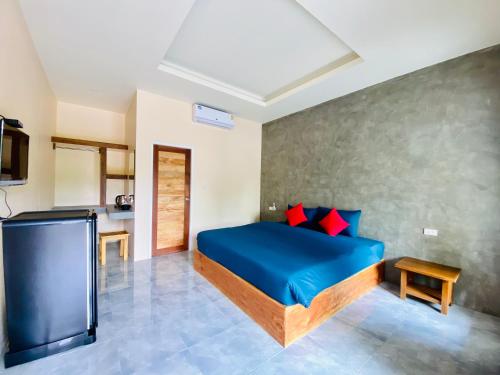 a bedroom with a bed with blue sheets and red pillows at Kohyao Non Bay in Ban Nai Wat