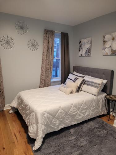 a bedroom with a bed with white sheets and a window at City vibes in Philadelphia