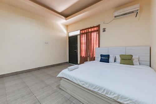 StalkudoにあるUrbanview Hotel Garuda Sky Inn Balikpapan by RedDoorzのベッドルーム(白いベッド1台、窓付)
