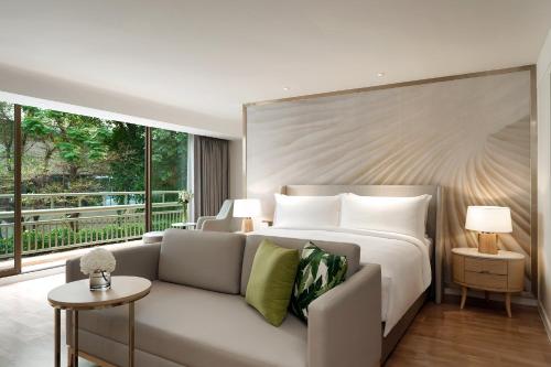 曼谷Mövenpick Hotel Bangkok Ploenchit BDMS的一间带床、沙发和窗户的卧室