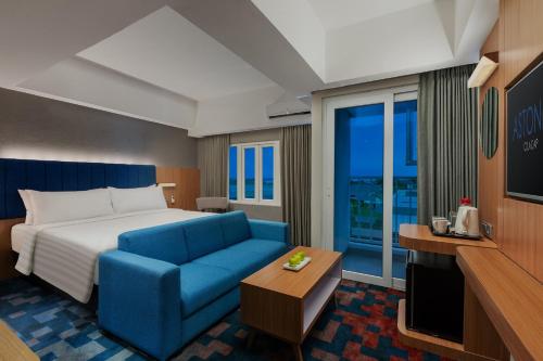 a hotel room with a bed and a blue couch at ASTON Inn Cilacap in Cilacap