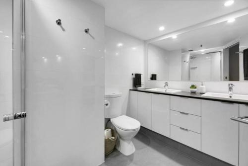 a white bathroom with a toilet and two sinks at Gemini Court - Hosted by Burleigh Letting in Gold Coast