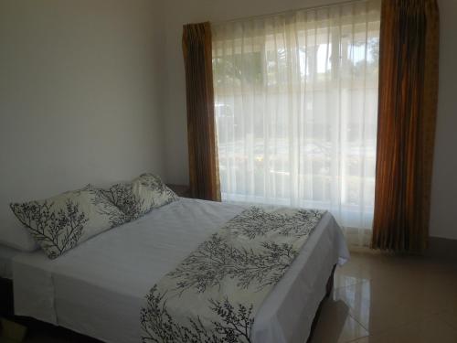 1 dormitorio con 1 cama y una ventana con cortinas en Condominio Tropical villa 2, en Jacó