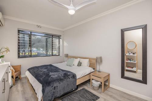 a white bedroom with a bed and a mirror at Gone Coastal in Cape Town