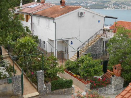 une maison blanche avec des escaliers et des fleurs sur une colline dans l'établissement Apartment Goran - sea view, à Okrug Donji