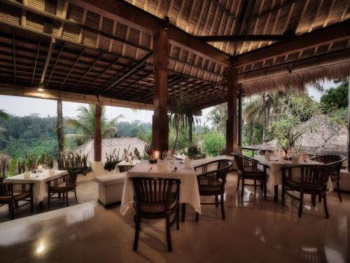 a restaurant with tables and chairs and a large window at Nandini Jungle by Hanging Gardens in Payangan