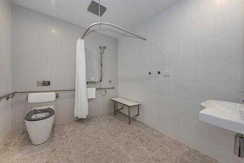 a white bathroom with a toilet and a sink at Littomore Suites Kingswood in Penrith