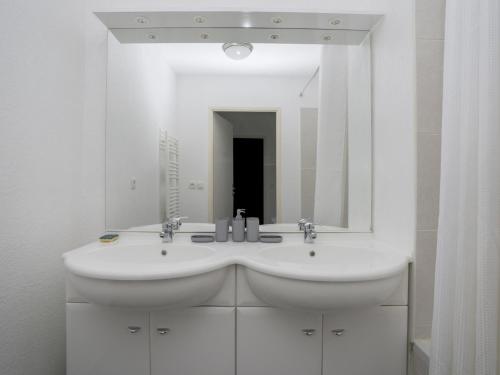 une salle de bain blanche avec un lavabo et un miroir dans l'établissement Appartement T3 à 50m de l'océan avec terrasse, parking et Wi-Fi - Refait à neuf, centre de Biscarrosse - FR-1-521-155, à Biscarrosse