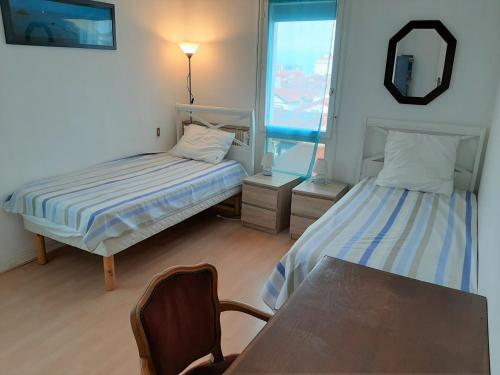 Cette chambre comprend 2 lits, une table et un miroir. dans l'établissement Appartement Saint-Jean-de-Luz, 4 pièces, 6 personnes - FR-1-239-598, à Saint-Jean-de-Luz