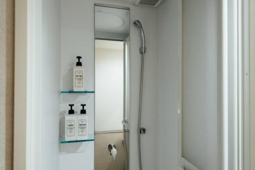 La salle de bains est pourvue d'un miroir et d'une douche avec deux distributeurs de savon. dans l'établissement Bird Place log Tokyo #KS1, à Tokyo