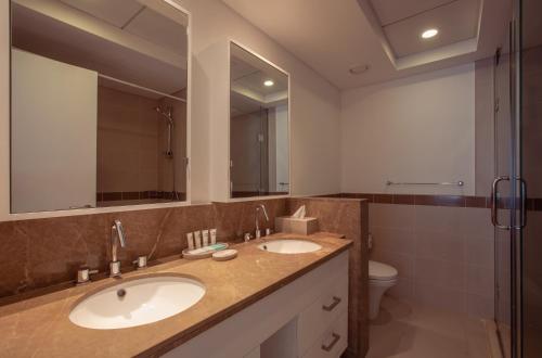 łazienka z 2 umywalkami, toaletą i lustrem w obiekcie Signature Burj Khalifa And Fountain View Residence w Dubaju