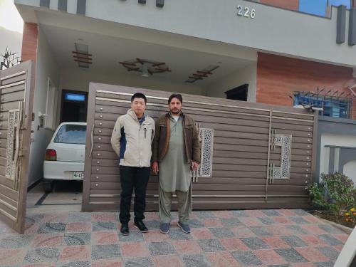 two people standing in front of a house at Lavish Inn Islamabad in Islamabad