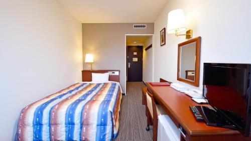 a hotel room with a bed and a desk with a television at Hotel GRANDSPA AVENUE in Asakura