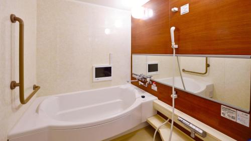 a bathroom with a large white tub and a sink at Hotel GRANDSPA AVENUE in Asakura