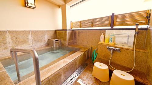 a bathroom with a bath tub and a toilet at Hotel GRANDSPA AVENUE in Asakura