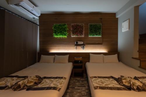 two beds in a room with green plants on the wall at -Musée Villa- in Nakijin