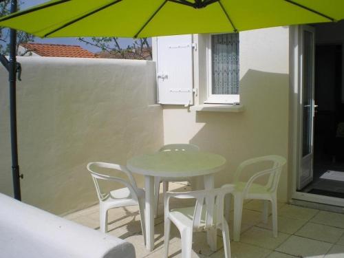 ein Tisch und Stühle und ein Sonnenschirm auf einer Terrasse in der Unterkunft Maison 2 pièces avec WiFi, Dolus-d'Oléron - FR-1-246A-350 in Dolus d'Oléron