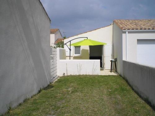 un parasol vert sur une clôture blanche dans l'établissement Charmante maison avec jardin, proche commerces et plages, WiFi inclus - Dolus-d'Oléron - FR-1-246A-350, à Dolus-d'Oléron