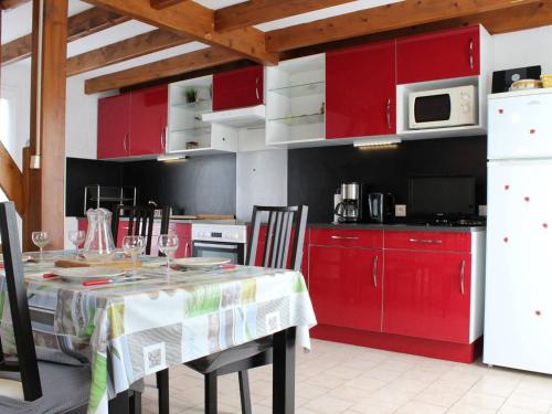 une cuisine avec des placards rouges et une table avec des chaises dans l'établissement Maison de Vacances à Oléron : Proche Port, Plage, Jardin, Terrasse, Garage - 6 Couchages - FR-1-246A-62, à Saint-Pierre-dʼOléron