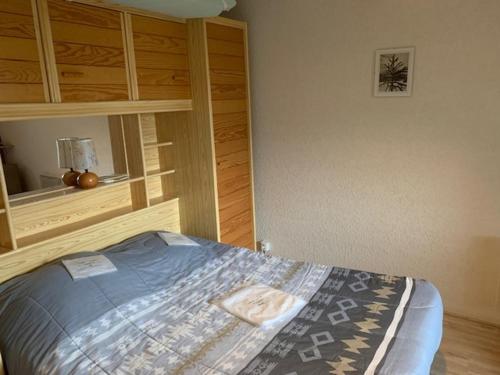 une chambre avec un lit avec une armoire en bois dans l'établissement F2 bis tout confort avec balcon au pied des pistes, parking et local à skis, Mont-Dore - FR-1-415-100, à Le Mont-Dore