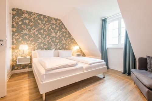 a bedroom with a white bed with a floral wallpaper at Haus Ameland, App 3 in Wenningstedt