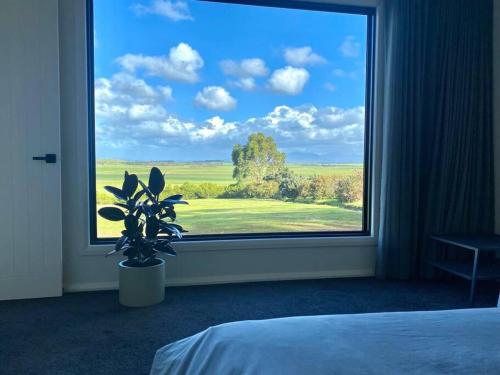 een slaapkamer met een groot raam met een potplant bij Wamoon Retreat Apartment Luxury Gateway to Wilsons Prom in Yanakie