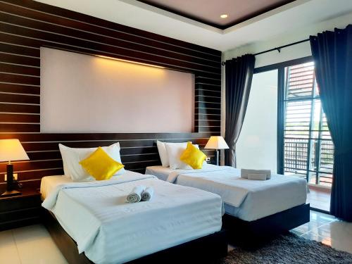 2 Betten in einem Hotelzimmer mit einem großen Fenster in der Unterkunft Purimas Resortel in Rawai Beach