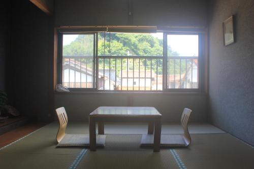 einen Tisch und zwei Stühle in einem Zimmer mit Fenster in der Unterkunft Annex higashifujita in Moroyose