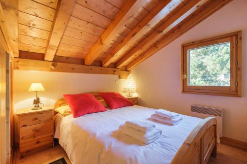 Schlafzimmer mit einem Bett mit roten Kissen und einem Fenster in der Unterkunft Village des Oursons C - Happy Rentals in Chamonix-Mont-Blanc