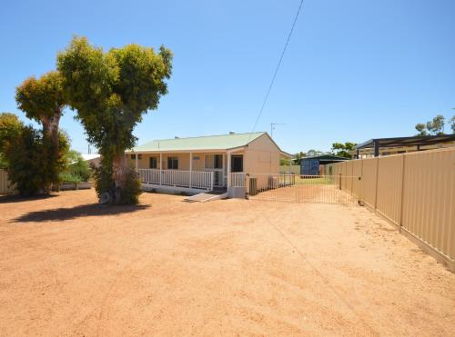 a house with a fence in front of a dirt yard at Surf Caster - Kalbarri, WA in Kalbarri