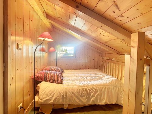 une chambre avec un lit dans une cabane en bois dans l'établissement Appartement cosy avec mezzanine, au pied des pistes à Combloux, parking inclus - FR-1-560-25, à Combloux