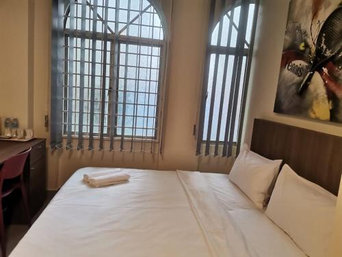 1 dormitorio con 1 cama blanca grande y 2 ventanas en SCC Hotel Chinatown en Kuala Lumpur