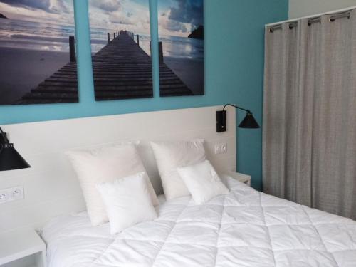 ein Schlafzimmer mit einem weißen Bett mit drei Bildern an der Wand in der Unterkunft Appartement La Tranche-sur-Mer, 2 pièces, 4 personnes - FR-1-194-221 in La Tranche-sur-Mer