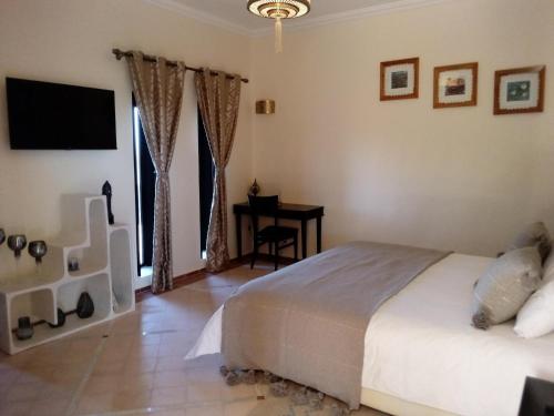 a bedroom with a bed and a desk and a television at Le petit Château des Anges in Marrakech
