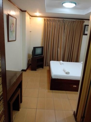 a small room with a bed and a television at Darunday Manor in Tagbilaran City