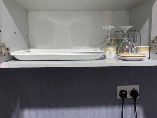 a shelf in a kitchen with some dishes on it at Big Studio Unit in Lekki phase 1 - Kitchen, Washer, 24-7 light, WiFi & Netflix in Lagos