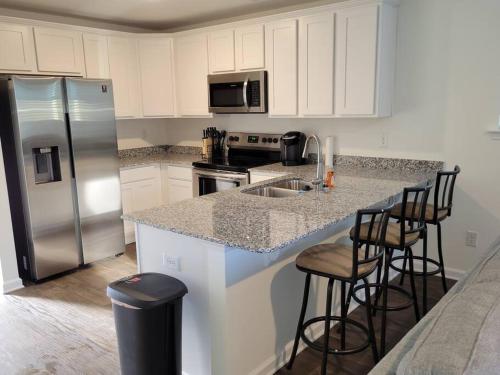 a kitchen with a sink and a refrigerator and stools at SC 3755 New 2 bedroom Townhouse Ft Jackson & USC in Columbia