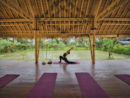 a woman is doing yoga in a pavilion at Nandini Jungle by Hanging Gardens in Payangan