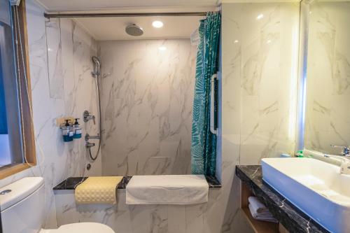 a bathroom with a shower and a toilet and a sink at Kenting Long Beach Hotel in Checheng