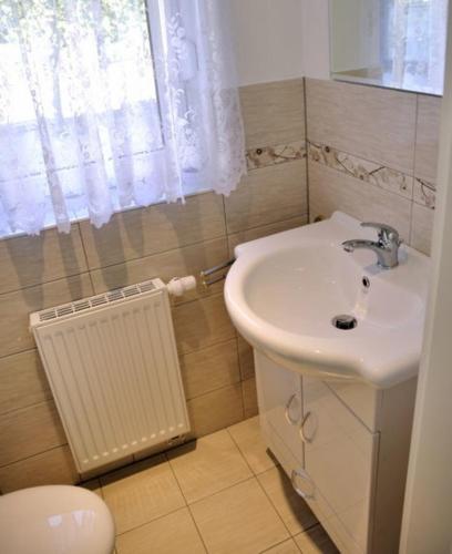 a bathroom with a white sink and a window at La Vida Suite in Hoppegarten