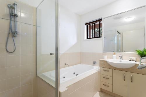 a bathroom with a tub and a sink and a shower at Little Whale House in Mudjimba