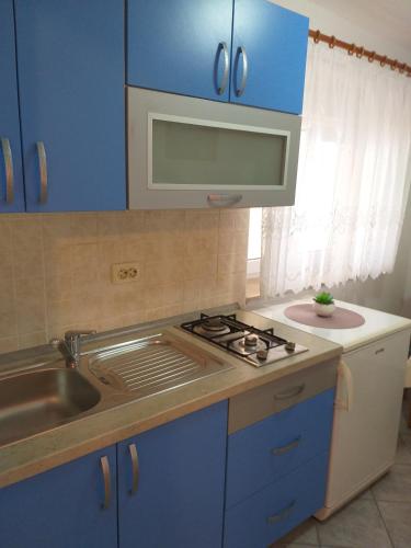 a kitchen with blue cabinets and a sink and a stove at Apartment Ante K A1 in Metajna
