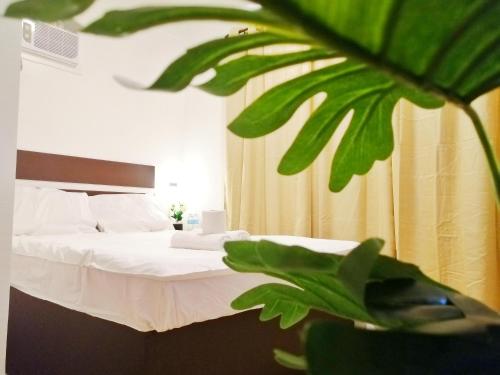 sypialnia z łóżkiem z białą pościelą i rośliną w obiekcie VG Pension & Residences w mieście Adlawon