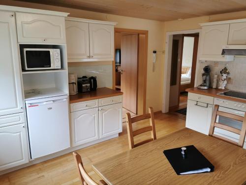kuchnia z białymi szafkami, stołem i kuchenką mikrofalową w obiekcie Haus Post OG-Wohnung w mieście Todtnau