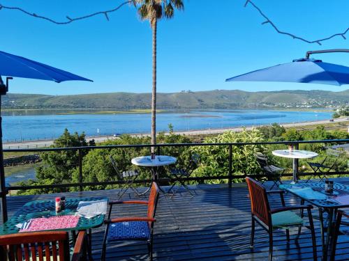 a deck with tables and chairs and a view of the water at Lagoon Lodge in Knysna