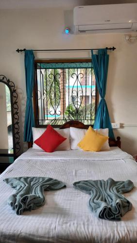 a bed with colorful pillows on it with a window at Tropical Wave Hostel Morjim in Morjim