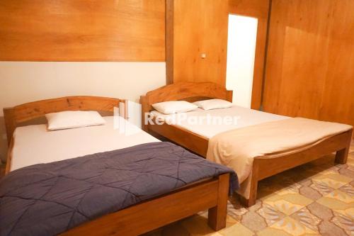 two beds in a room with wood paneling at Jogo Segoro Homestay Mitra RedDoorz near Pantai Sundak Gunungkidul in Ngandong